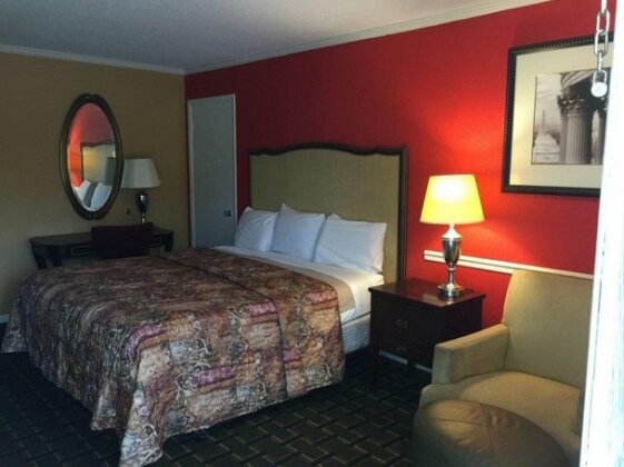 Guest room with a large bed, bedside lamp and sitting chair